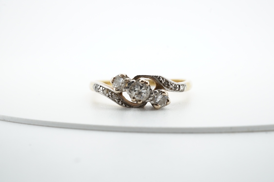 A three-stone diamond ring, early 20th century, centring on a diagonal line of three circular-cut diamonds totalling approximately 0.24 carats, to asymmetrical shoulders set with smaller rose-cut diamonds, mounted in gol